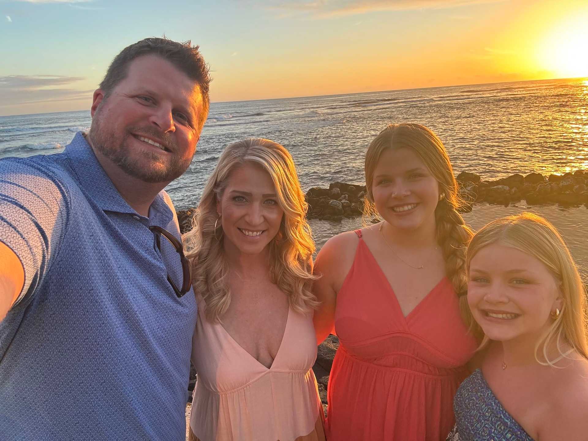 Family smiles at sunset by the ocean.