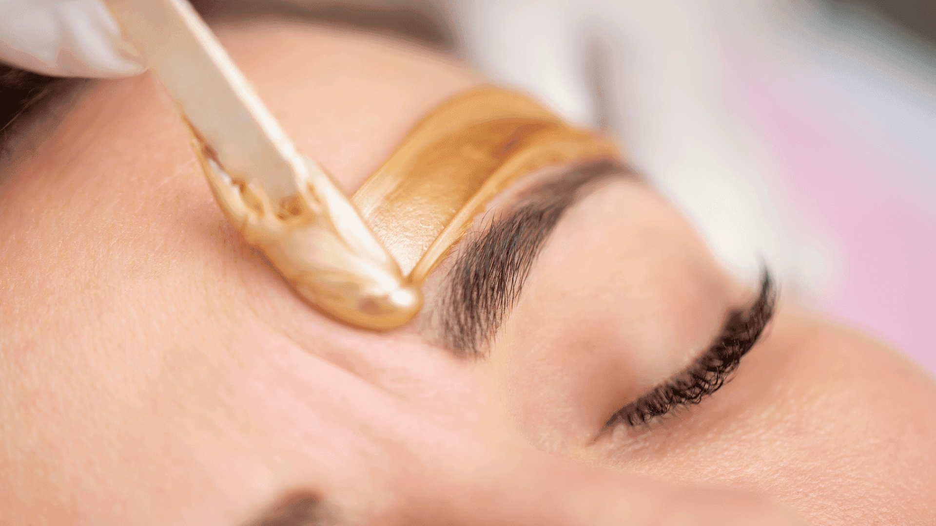 Eyebrow being shaped with wax application. Close-up of beauty treatment process.